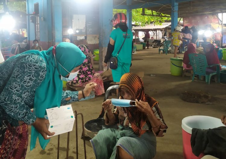 Seorang pengurus TP PKK Kabupaten Lembata membagikan masker bagi pedagang di pasar TPI Lewoleba, Selasa (6/7/2021) / Foto : BentaraNet