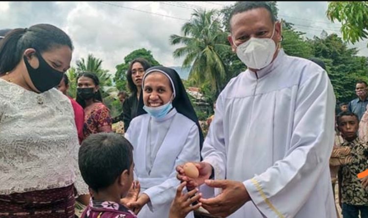 Pastor Paroki Kristus Raja Wangatoa, RD Kristo Soge membagi telur paskah untuk anak-anak usai Misa Paskah, Minggu, 17 April 2022 / Sumber Foto : aksinews.id
